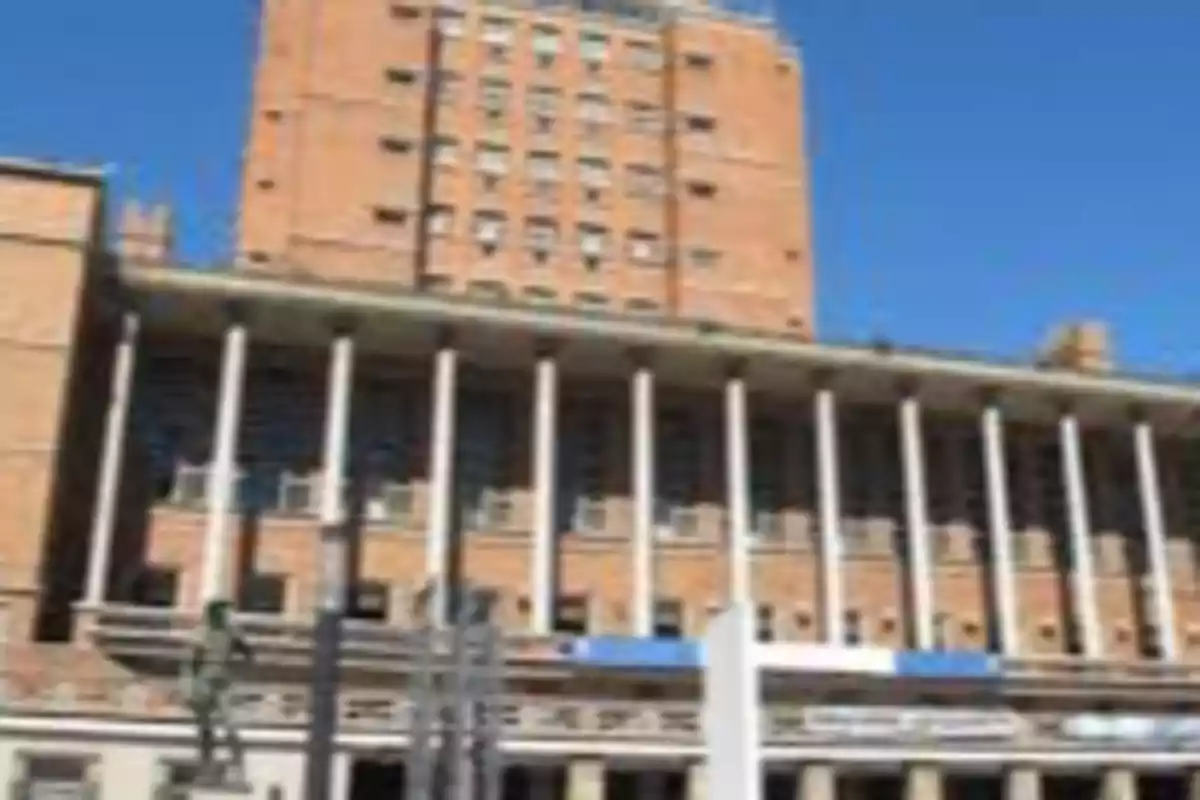 Edificio de ladrillo con columnas blancas en la fachada y cielo despejado de fondo