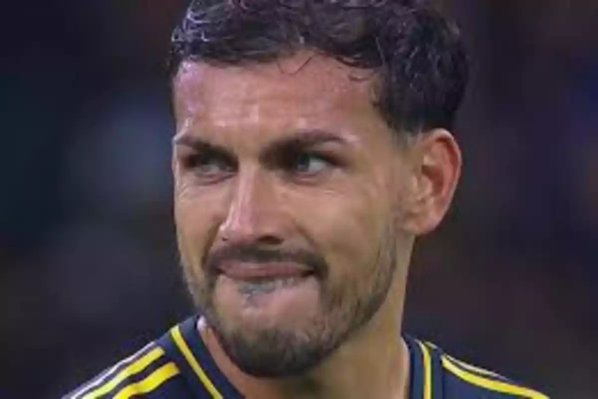 Hombre con expresión de frustración y camiseta deportiva azul con amarillo Hombre con expresión de frustración y camiseta deportiva azul con amarillo