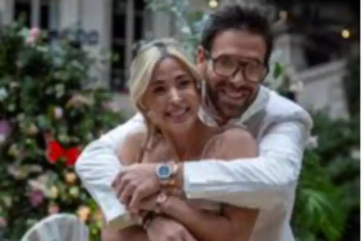 Couple hugging and smiling in an outdoor setting with flowers in the background Couple hugging and smiling in an outdoor setting with flowers in the background
