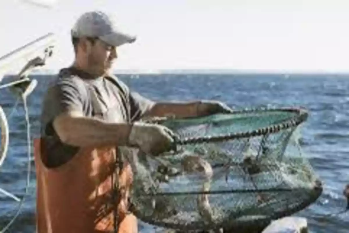 Pescador sosteniendo una trampa de cangrejos sobre un bote en el mar Pescador sosteniendo una trampa de cangrejos sobre un bote en el mar