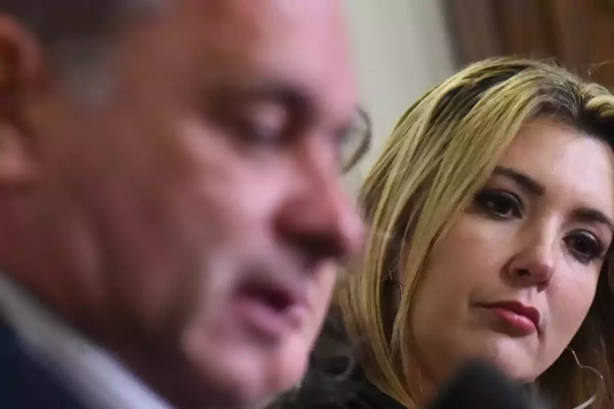 Una mujer rubia observa atentamente a un hombre desenfocado en primer plano durante una conversación seria Una mujer rubia observa atentamente a un hombre desenfocado en primer plano durante una conversación seria