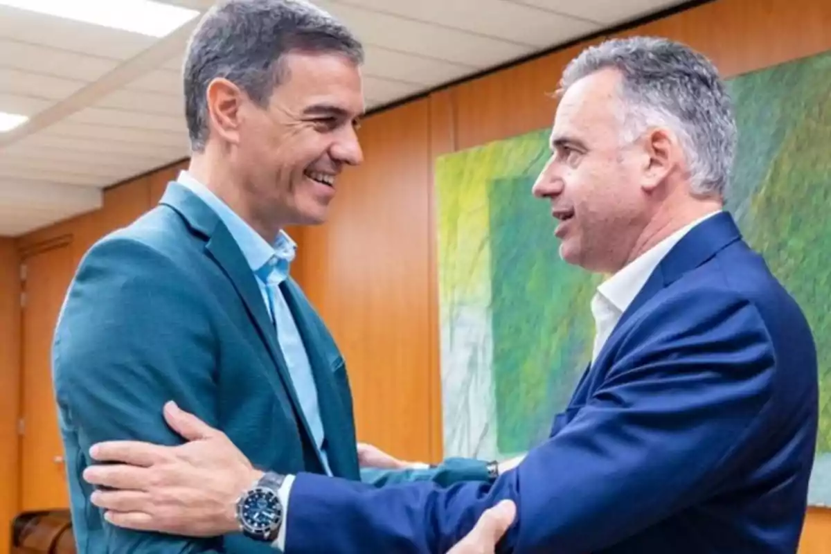 Dos hombres de traje se saludan sonrientes en una oficina con paredes de madera y un cuadro abstracto al fondo Dos hombres de traje se saludan sonrientes en una oficina con paredes de madera y un cuadro abstracto al fondo