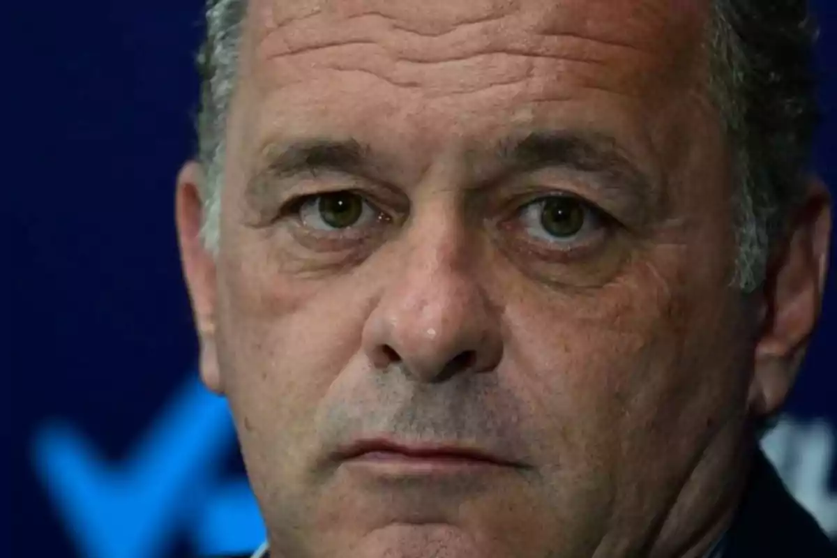 Primer plano del rostro de un hombre de expresión seria con fondo azul desenfocado Primer plano del rostro de un hombre de expresión seria con fondo azul desenfocado