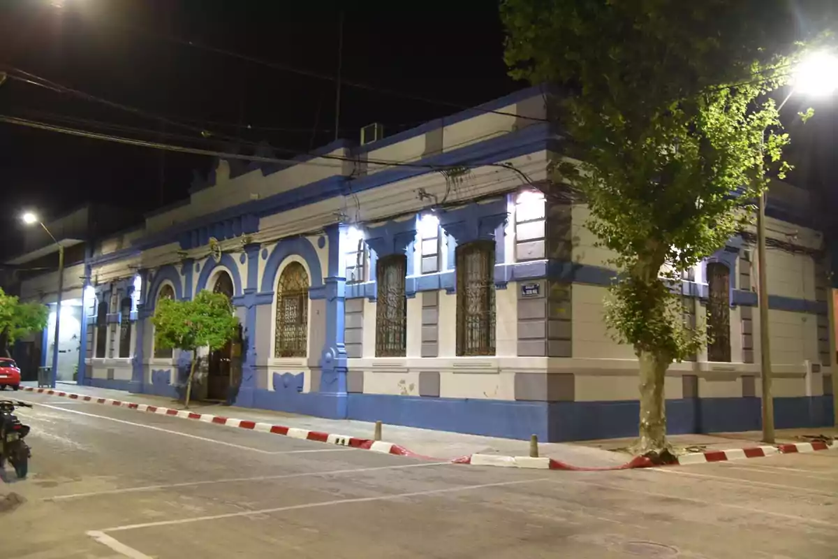 Old building with a blue and white facade illuminated by lanterns on a corner at night