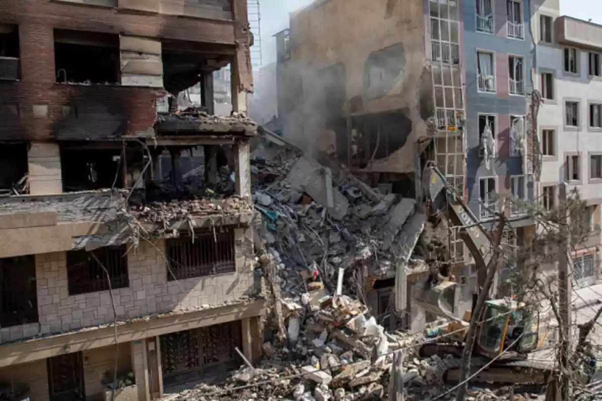 Edificio parcialmente destruido con escombros y una excavadora trabajando en la zona afectada Edificio parcialmente destruido con escombros y una excavadora trabajando en la zona afectada