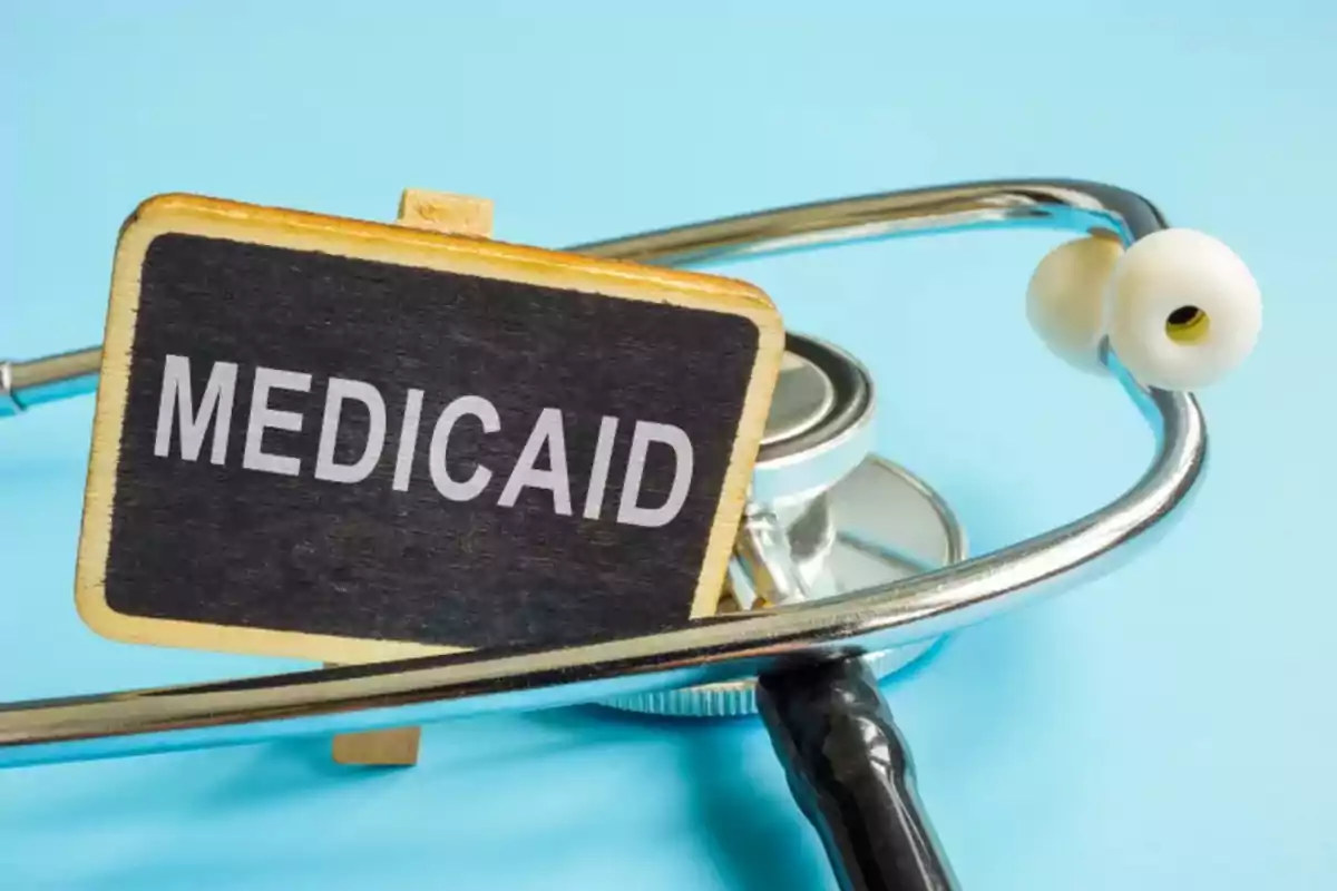Un estetoscopio junto a un letrero pequeño que dice Medicaid sobre un fondo azul Un estetoscopio junto a un letrero pequeño que dice Medicaid sobre un fondo azul