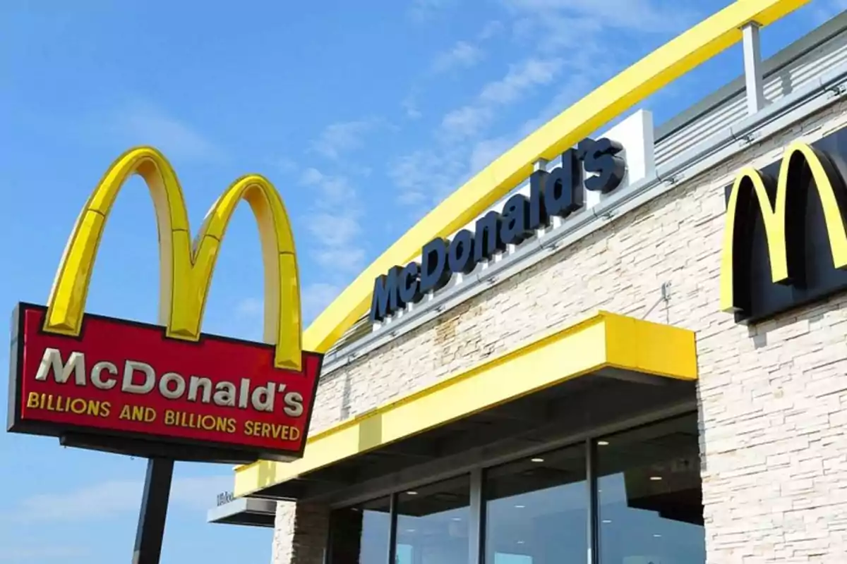 Facade of a McDonald's restaurant with the golden arches logo and a red sign under a blue sky