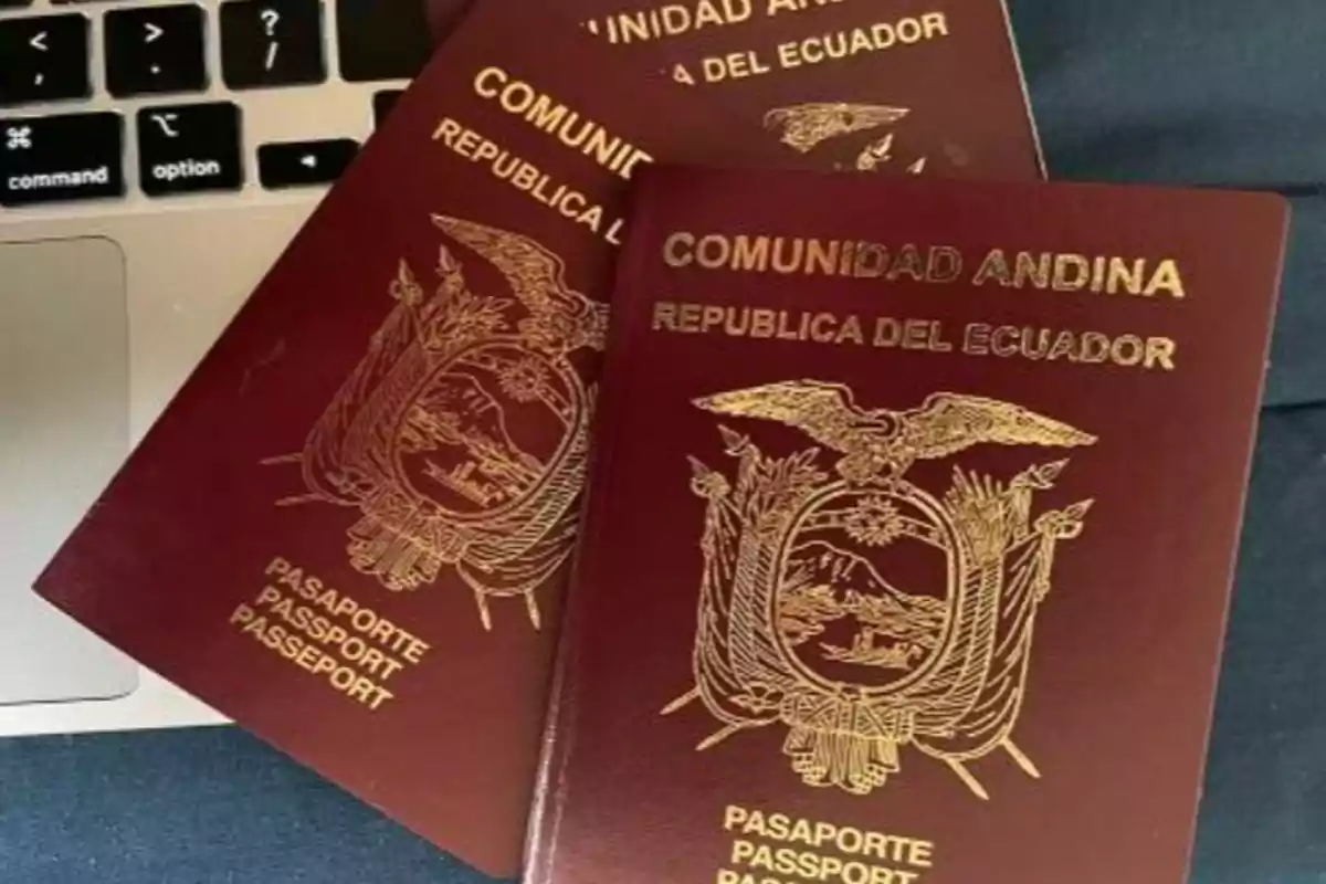 Tres pasaportes ecuatorianos de la Comunidad Andina sobre el teclado de una computadora portátil Tres pasaportes ecuatorianos de la Comunidad Andina sobre el teclado de una computadora portátil