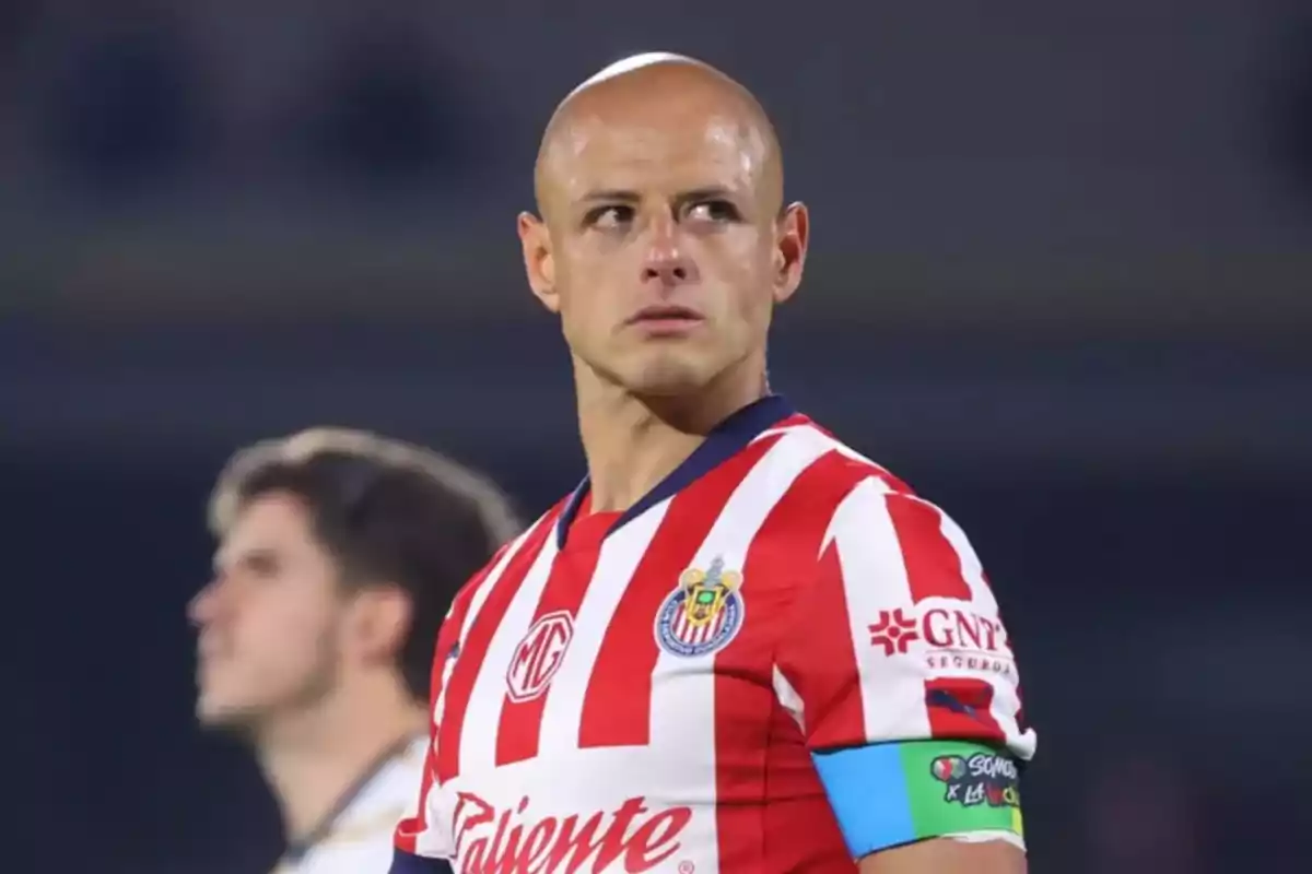Futbolista con uniforme de Chivas y gafete de capitán mirando hacia un lado en un estadio Futbolista con uniforme de Chivas y gafete de capitán mirando hacia un lado en un estadio