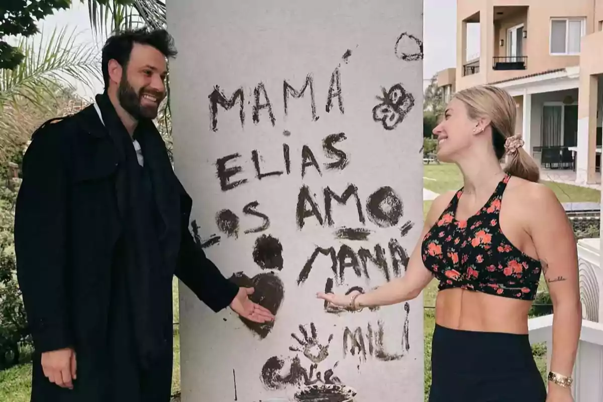 A man and a woman smile and point at a message written on a column that says A man and a woman smile and point at a message written on a column that says