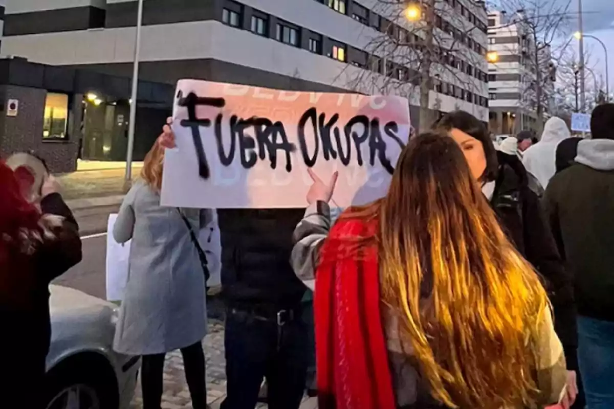 Several people are protesting in the street, and one of them is holding a sign with the message Several people are protesting in the street, and one of them is holding a sign with the message