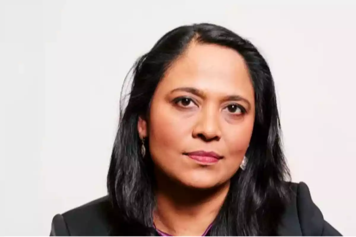 Dark-haired woman with straight hair and a serious expression, dressed in formal clothing, in front of a light background Dark-haired woman with straight hair and a serious expression, dressed in formal clothing, in front of a light background