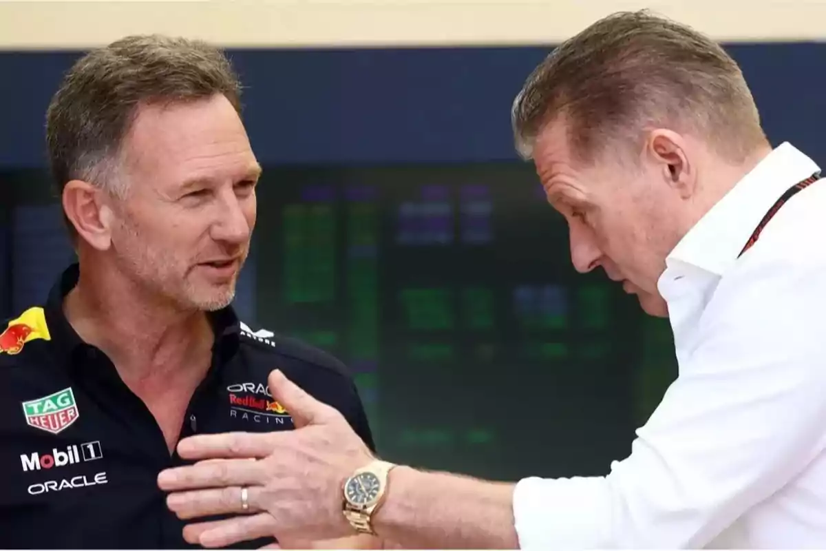 Two men are having a serious conversation; one of them is wearing a Red Bull Racing jersey and the other is wearing a white jersey. Both are gesturing as they speak. Two men are having a serious conversation; one of them is wearing a Red Bull Racing jersey and the other is wearing a white jersey. Both are gesturing as they speak.