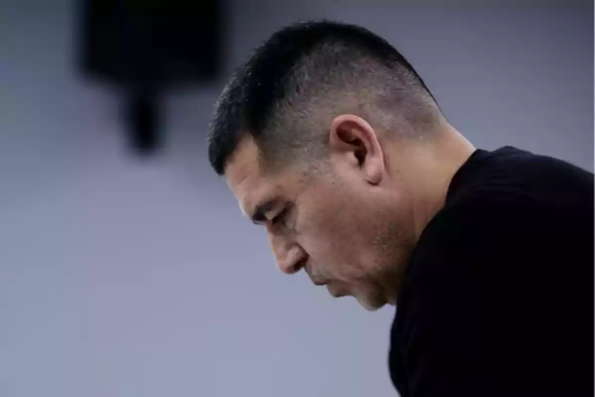 Hombre de perfil con expresión seria y cabeza inclinada hacia abajo en un ambiente interior Hombre de perfil con expresión seria y cabeza inclinada hacia abajo en un ambiente interior