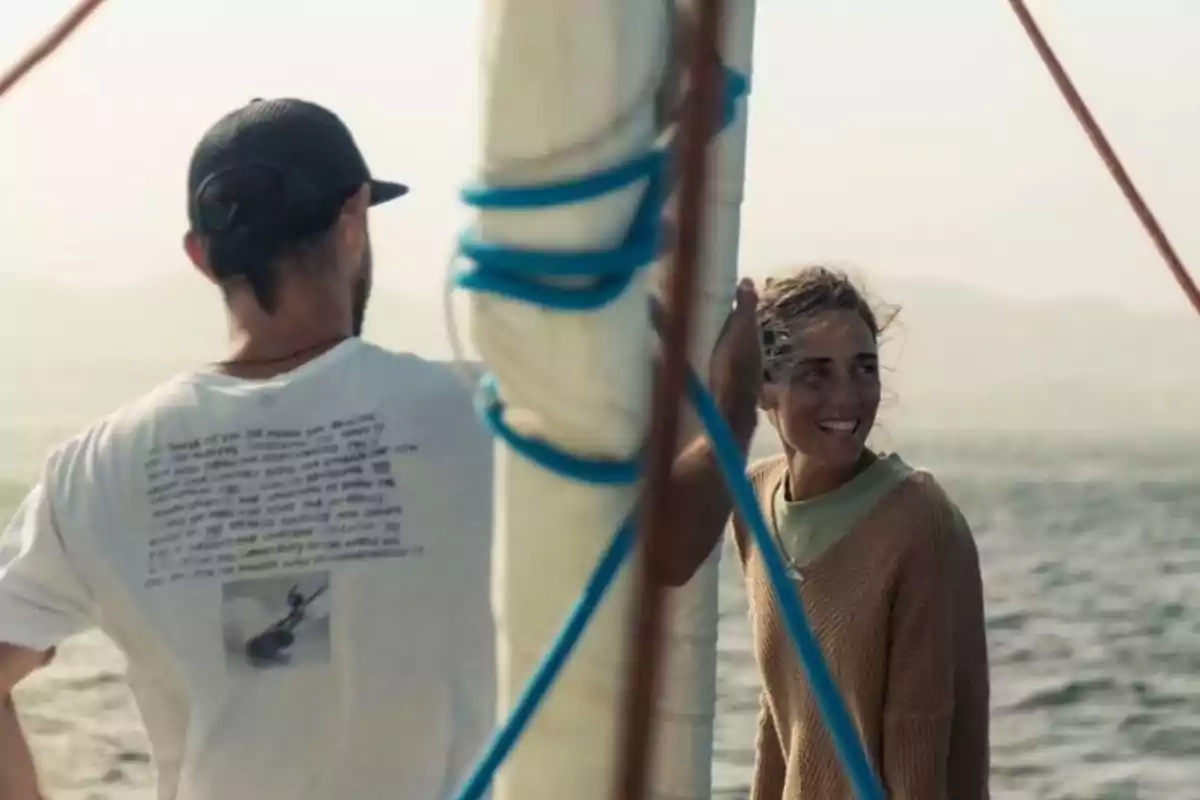 Two people talk and smile while sailing on a sailboat at sea. Two people talk and smile while sailing on a sailboat at sea.