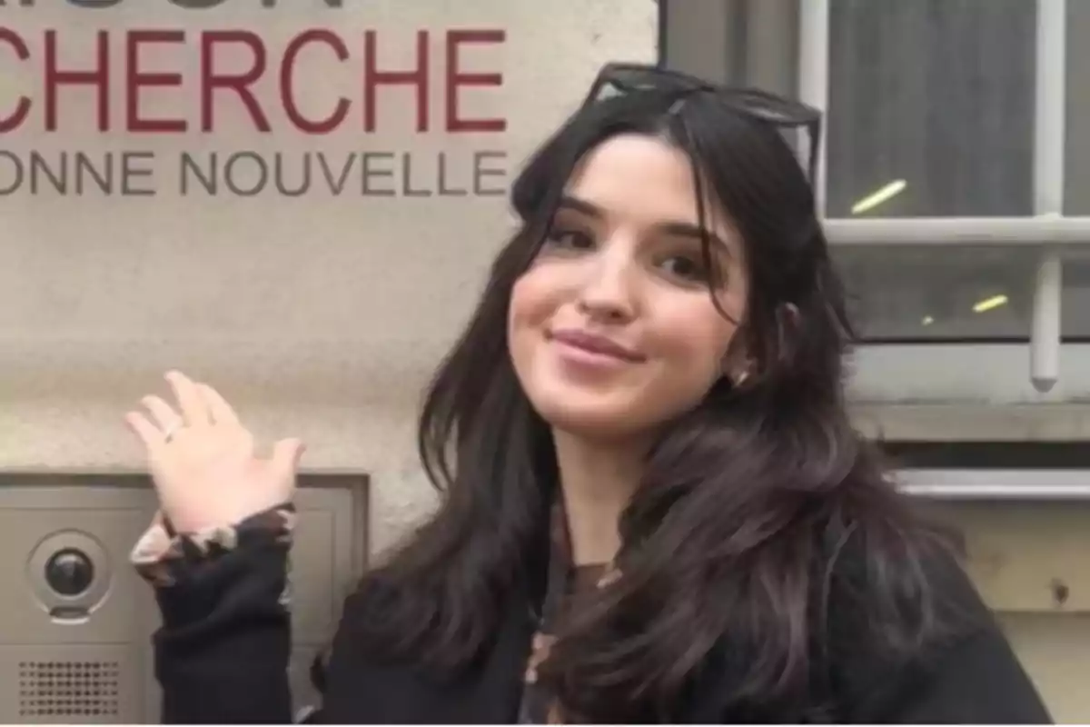 Young dark-haired person smiles and points to a sign on the wall that says Young dark-haired person smiles and points to a sign on the wall that says