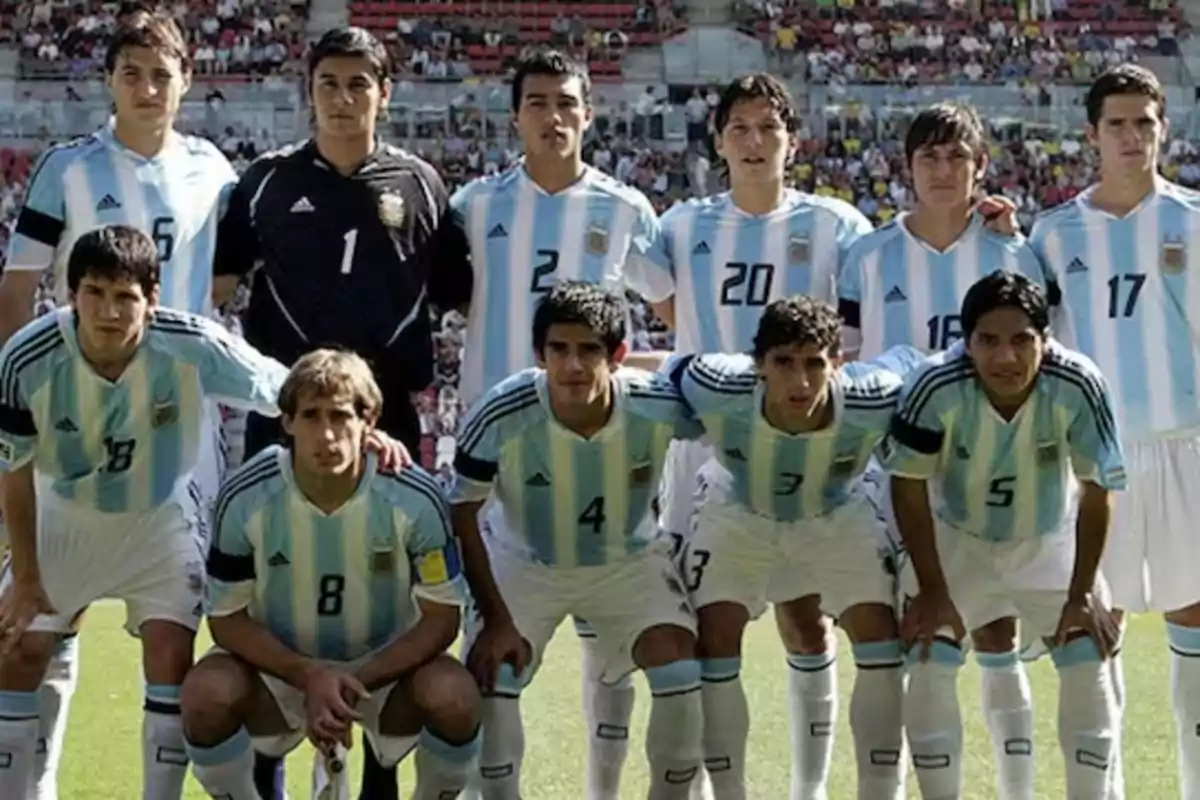 Eleven players from the Argentine national soccer team pose for the official photo before a match in a stadium full of fans.
