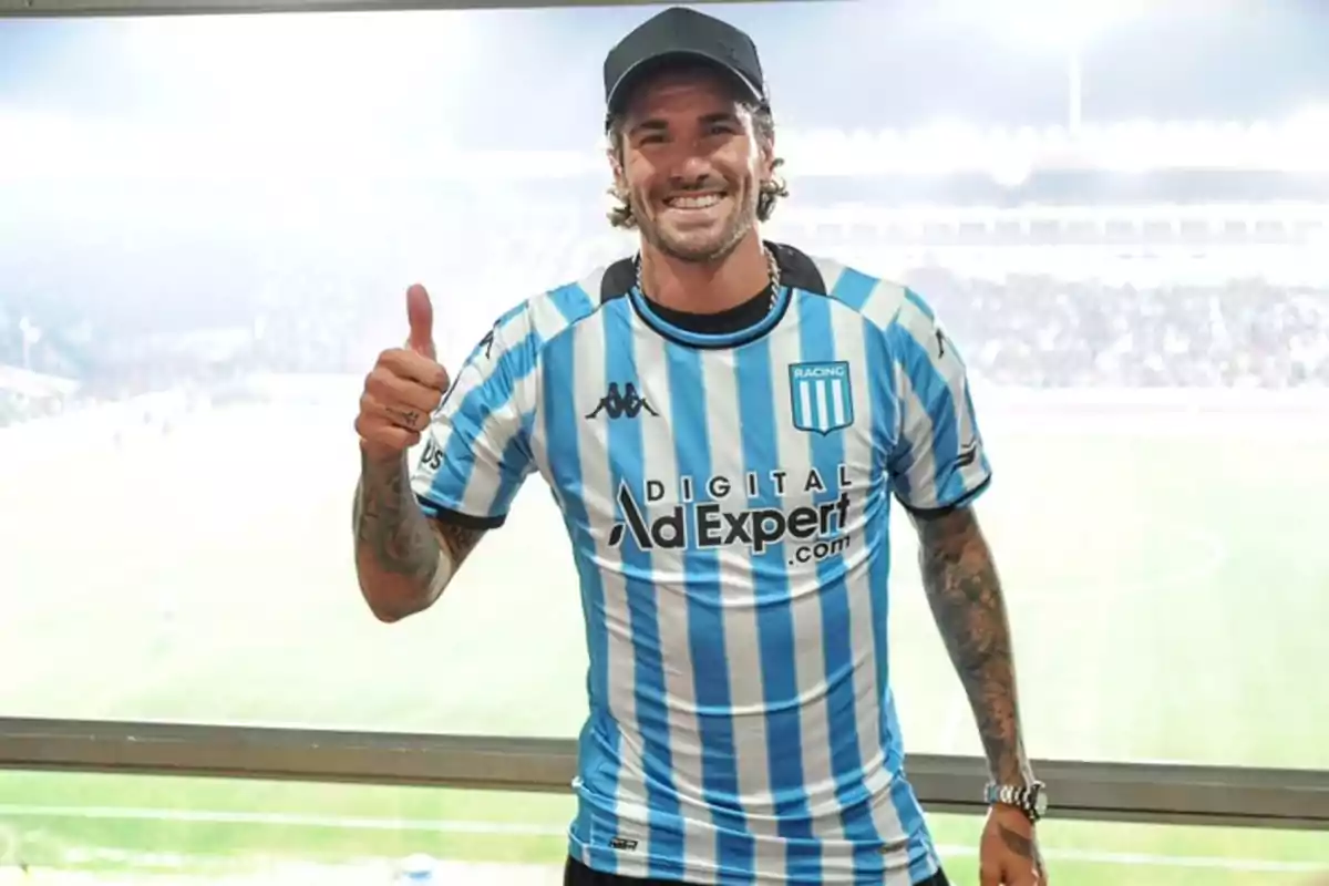 Hombre sonriente con gorra y camiseta de Racing Club levantando el pulgar en un estadio de fútbol Hombre sonriente con gorra y camiseta de Racing Club levantando el pulgar en un estadio de fútbol