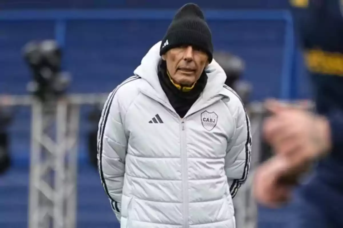 Older man wearing a black beanie and a white Boca Juniors jacket on a soccer field Older man wearing a black beanie and a white Boca Juniors jacket on a soccer field