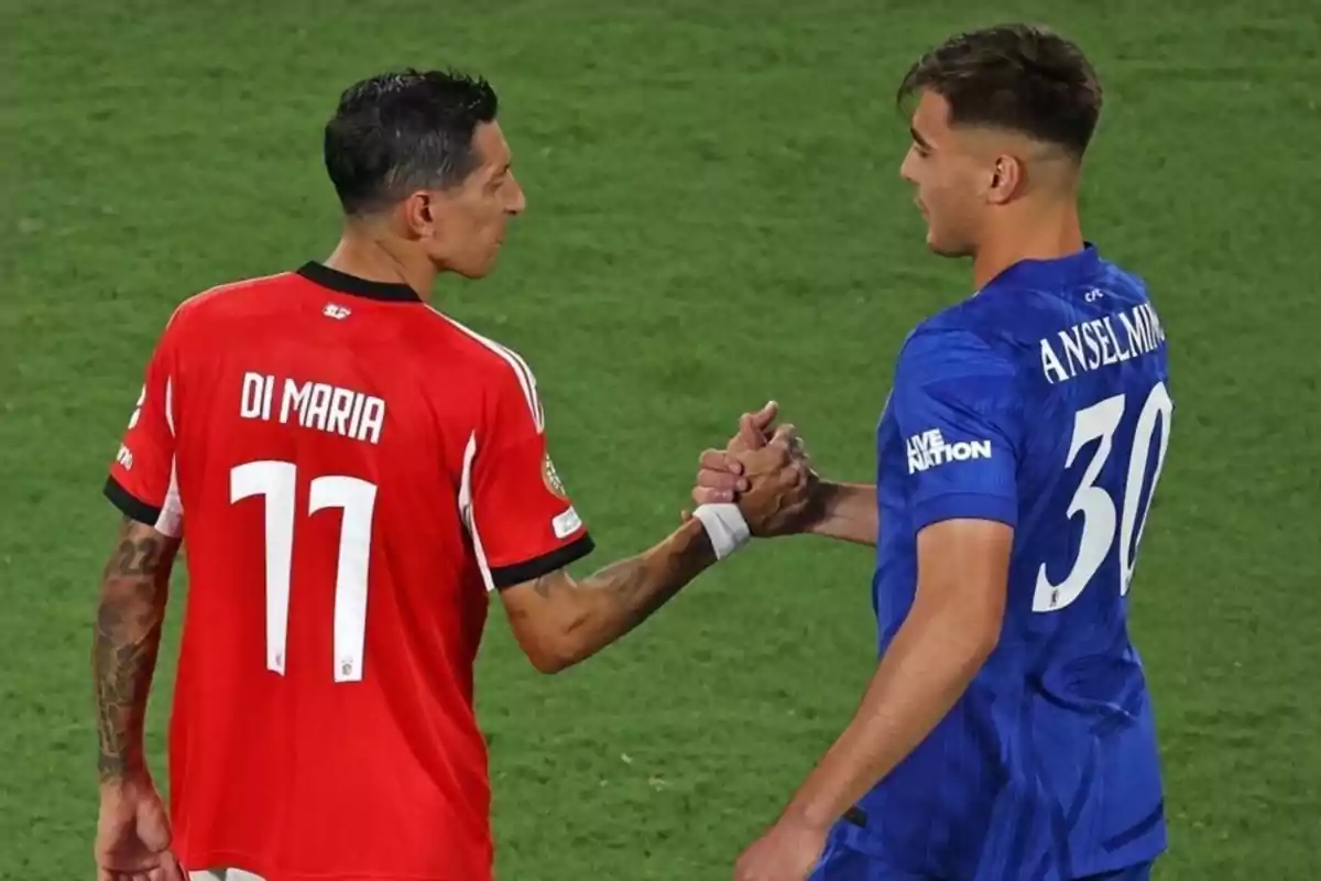 Dos futbolistas se saludan en el campo, uno con camiseta roja y el otro con camiseta azul Dos futbolistas se saludan en el campo, uno con camiseta roja y el otro con camiseta azul