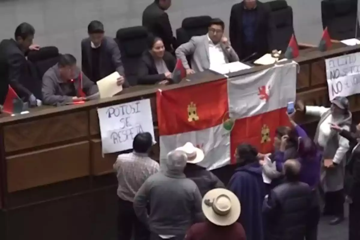 People gathered in a venue with flags and signs expressing protest messages related to Potosí People gathered in a venue with flags and signs expressing protest messages related to Potosí