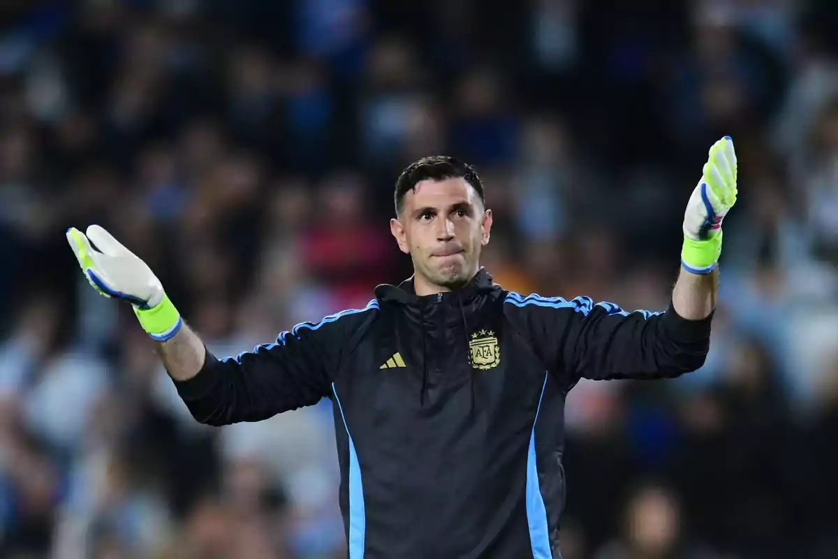 Portero de la selección argentina con guantes levantando ambos brazos en un estadio lleno de espectadores Portero de la selección argentina con guantes levantando ambos brazos en un estadio lleno de espectadores