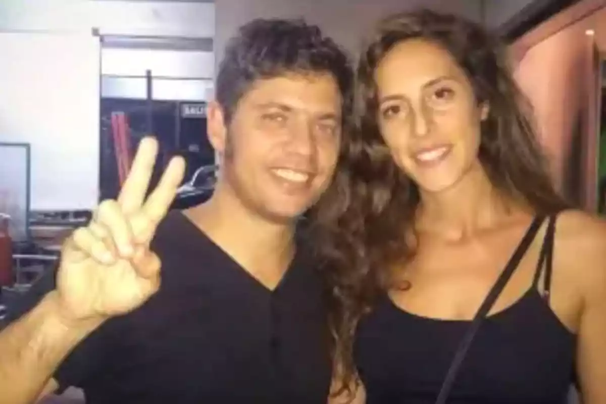 Dos personas jóvenes sonríen a la cámara mientras una de ellas hace el gesto de la paz con la mano
