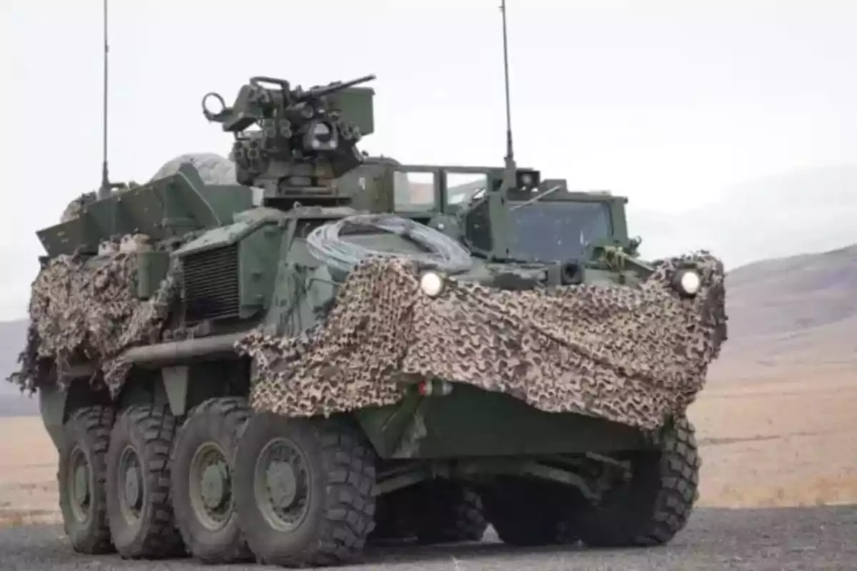 Eight-wheeled armored military vehicle partially covered with a camouflage net in an arid terrain Eight-wheeled armored military vehicle partially covered with a camouflage net in an arid terrain