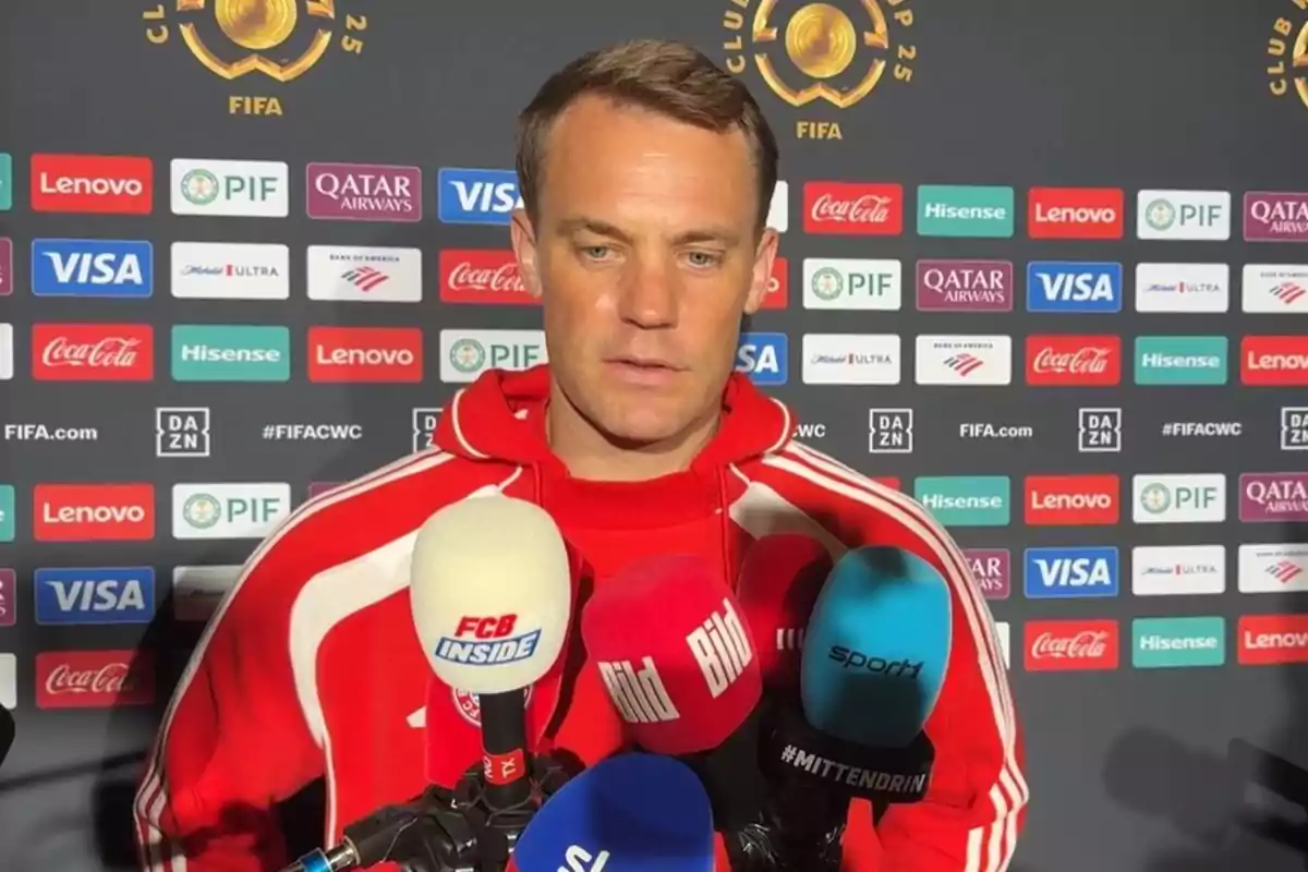 A player in a red sweatjersey gives an interview in front of several microphones and a backdrop with sponsor logos and the FIFA emblem. A player in a red sweatjersey gives an interview in front of several microphones and a backdrop with sponsor logos and the FIFA emblem.