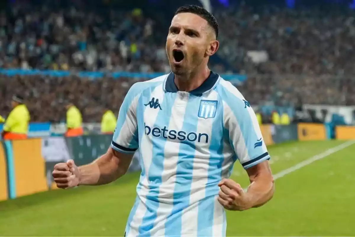 Racing Club player celebrating a goal with a clenched fist in a packed stadium. Racing Club player celebrating a goal with a clenched fist in a packed stadium.