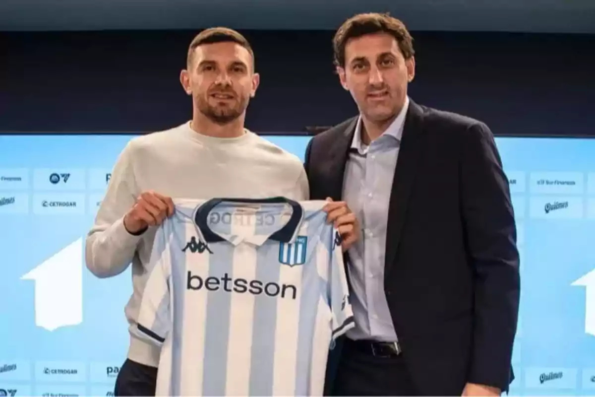 Two people pose together while one of them holds a Racing Club soccer jersey with the Betsson logo.