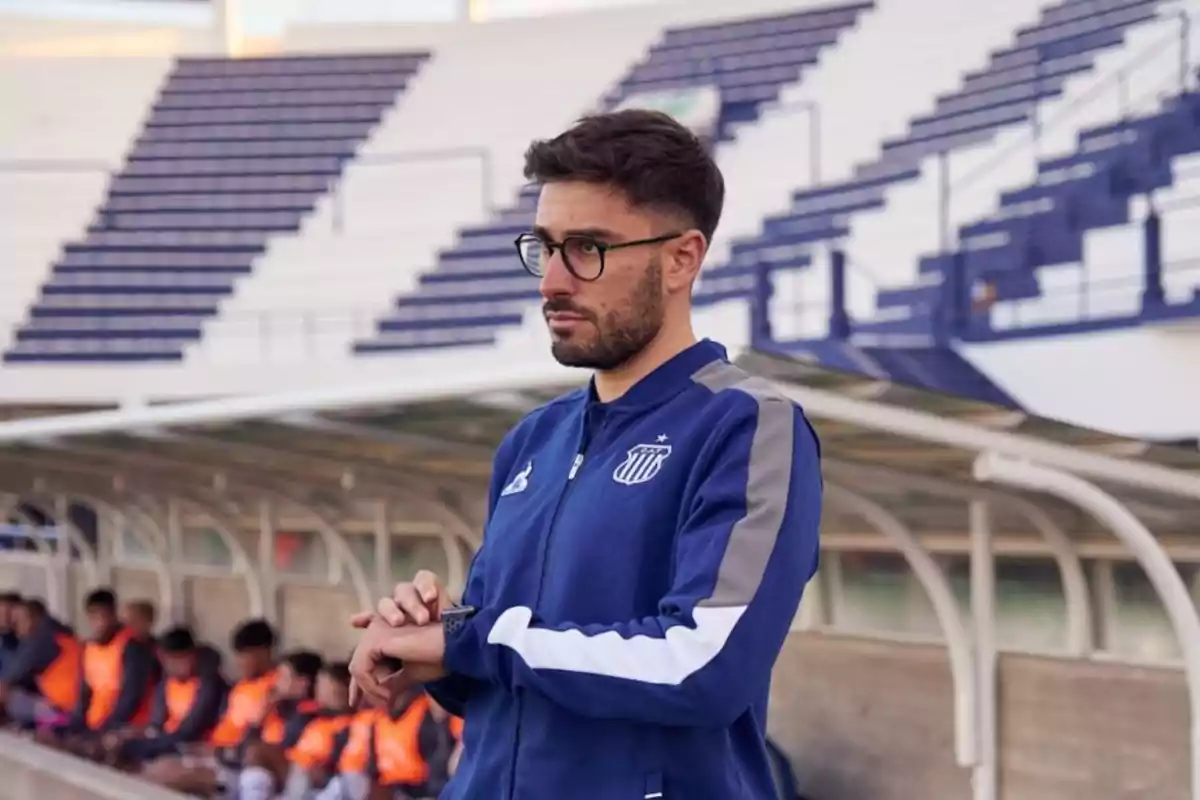 Entrenador de fútbol con gafas y chaqueta azul de Talleres de Córdoba observando el partido desde la zona técnica del estadio Entrenador de fútbol con gafas y chaqueta azul de Talleres de Córdoba observando el partido desde la zona técnica del estadio