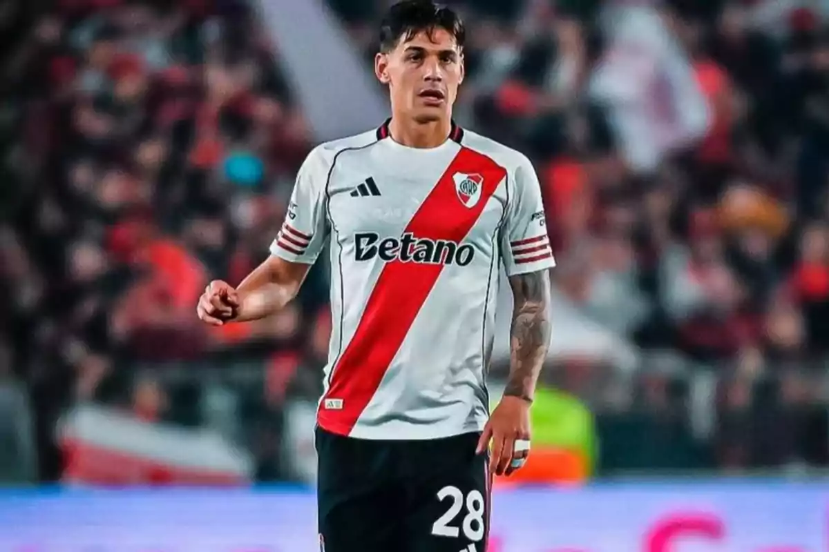 Soccer player wearing a white uniform with a red diagonal stripe in a stadium during a match