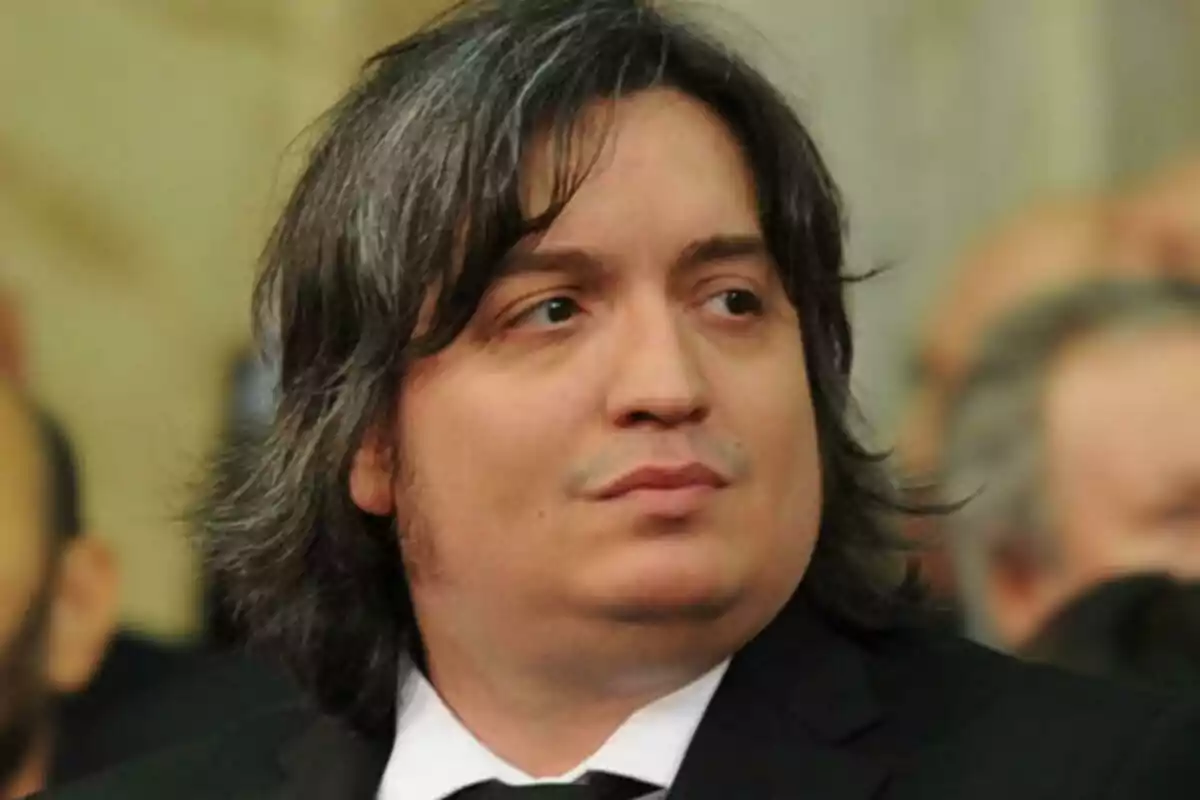Long-haired, dark-haired man wearing a black suit at a formal event