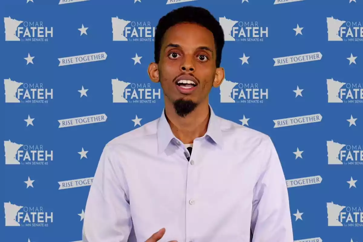 Man standing in a light-colored jersey in front of a blue background with stars and campaign texts that say Omar Fateh and Rise Together Man standing in a light-colored jersey in front of a blue background with stars and campaign texts that say Omar Fateh and Rise Together