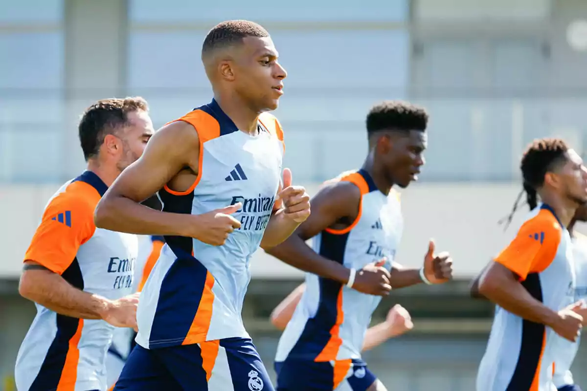 Several players train outdoors wearing Real Madrid training uniforms as they run together in a practice session. Several players train outdoors wearing Real Madrid training uniforms as they run together in a practice session.