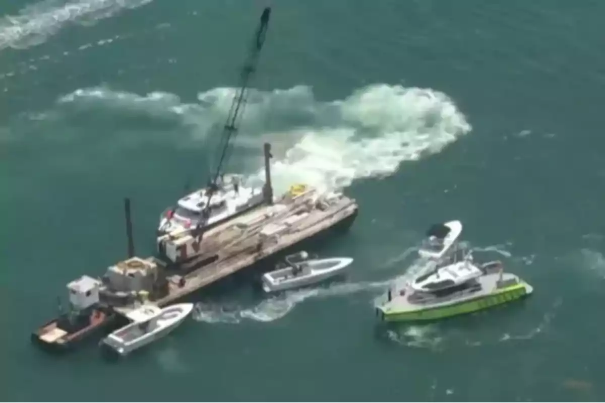 Varias embarcaciones rodean una plataforma con grúa en el mar, mientras se observa una gran turbulencia en el agua cercana. Varias embarcaciones rodean una plataforma con grúa en el mar, mientras se observa una gran turbulencia en el agua cercana.