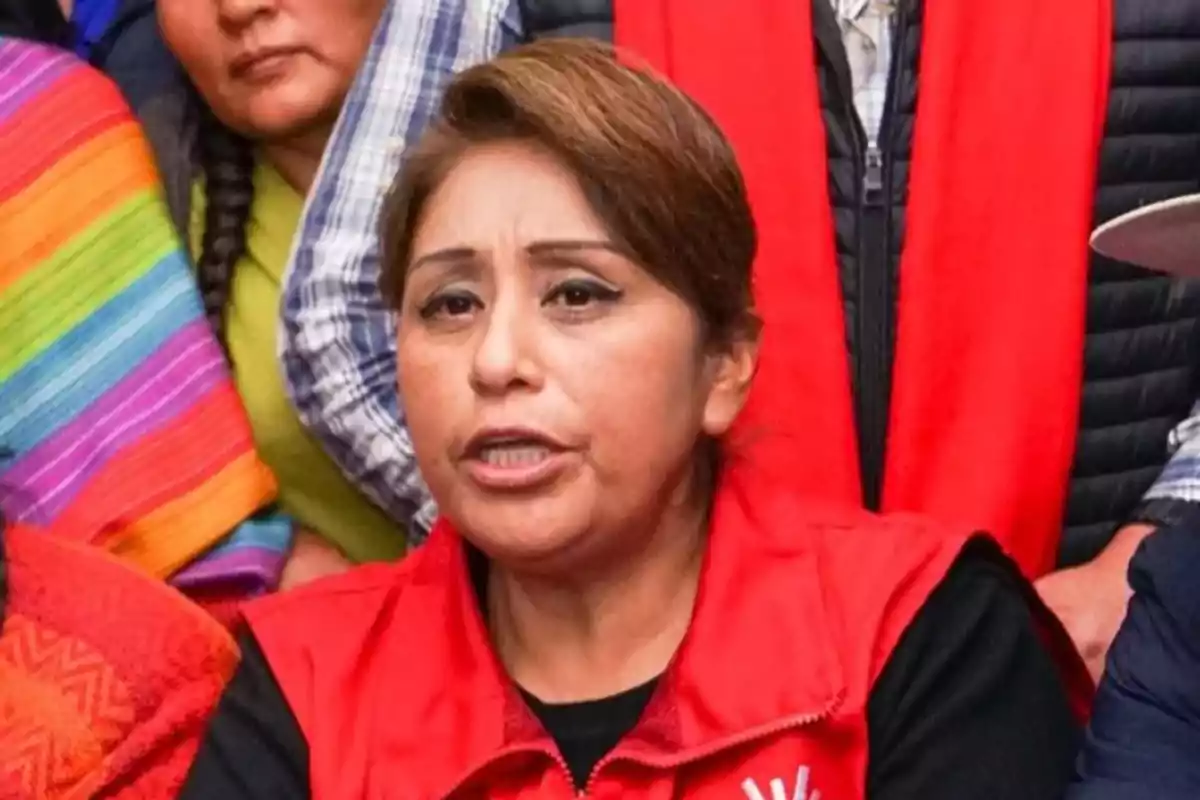 Short-haired brunette woman in a red jacket speaking in front of a group of people Short-haired brunette woman in a red jacket speaking in front of a group of people