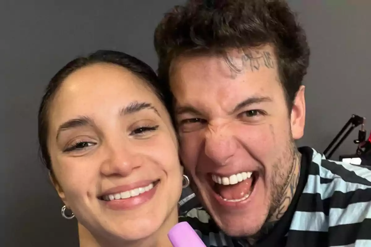 Dos personas jóvenes posan para una selfie, una de ellas sonríe y la otra hace una expresión divertida mostrando los dientes