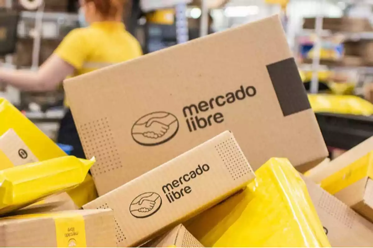 Mercado Libre boxes and packages stacked in a distribution center with a blurred person in the background