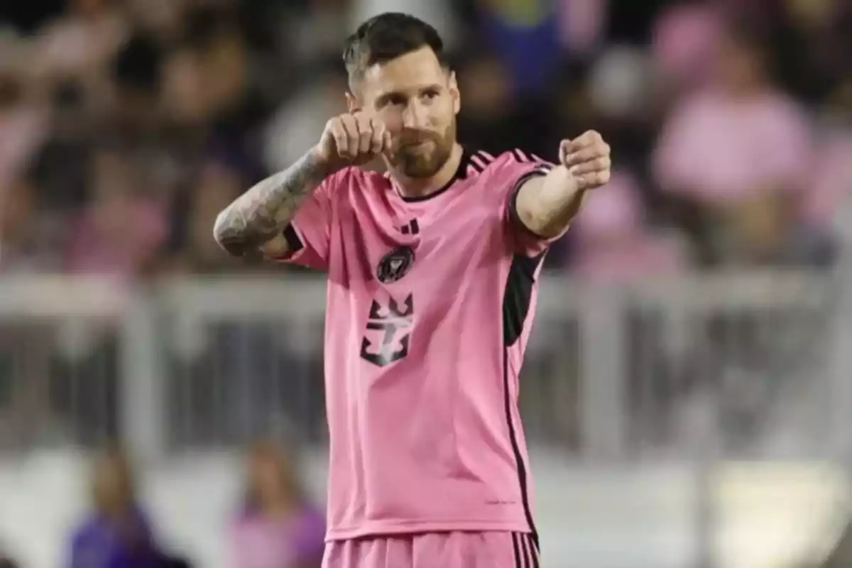 Soccer player in a pink uniform celebrating on the field, making a goalkeeper gesture with arms outstretched
