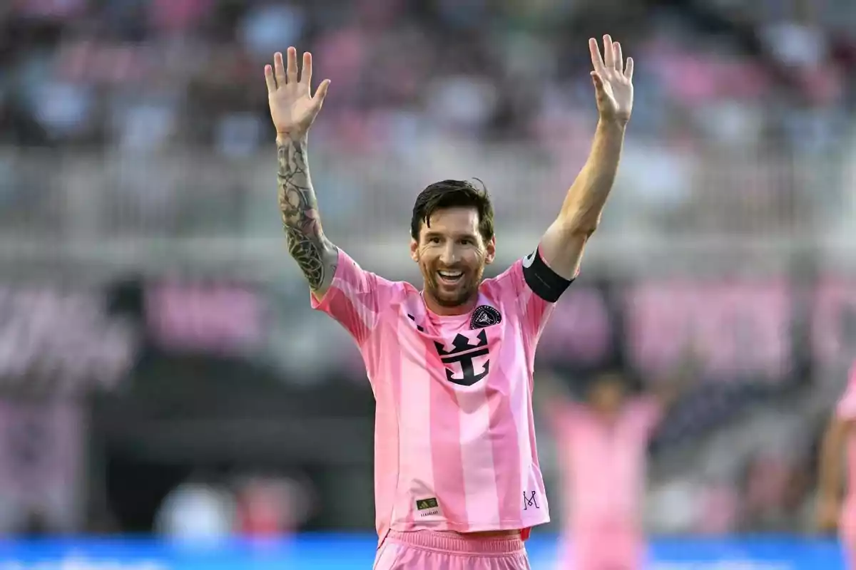 Soccer player in a pink uniform celebrating with arms raised in a stadium Soccer player in a pink uniform celebrating with arms raised in a stadium