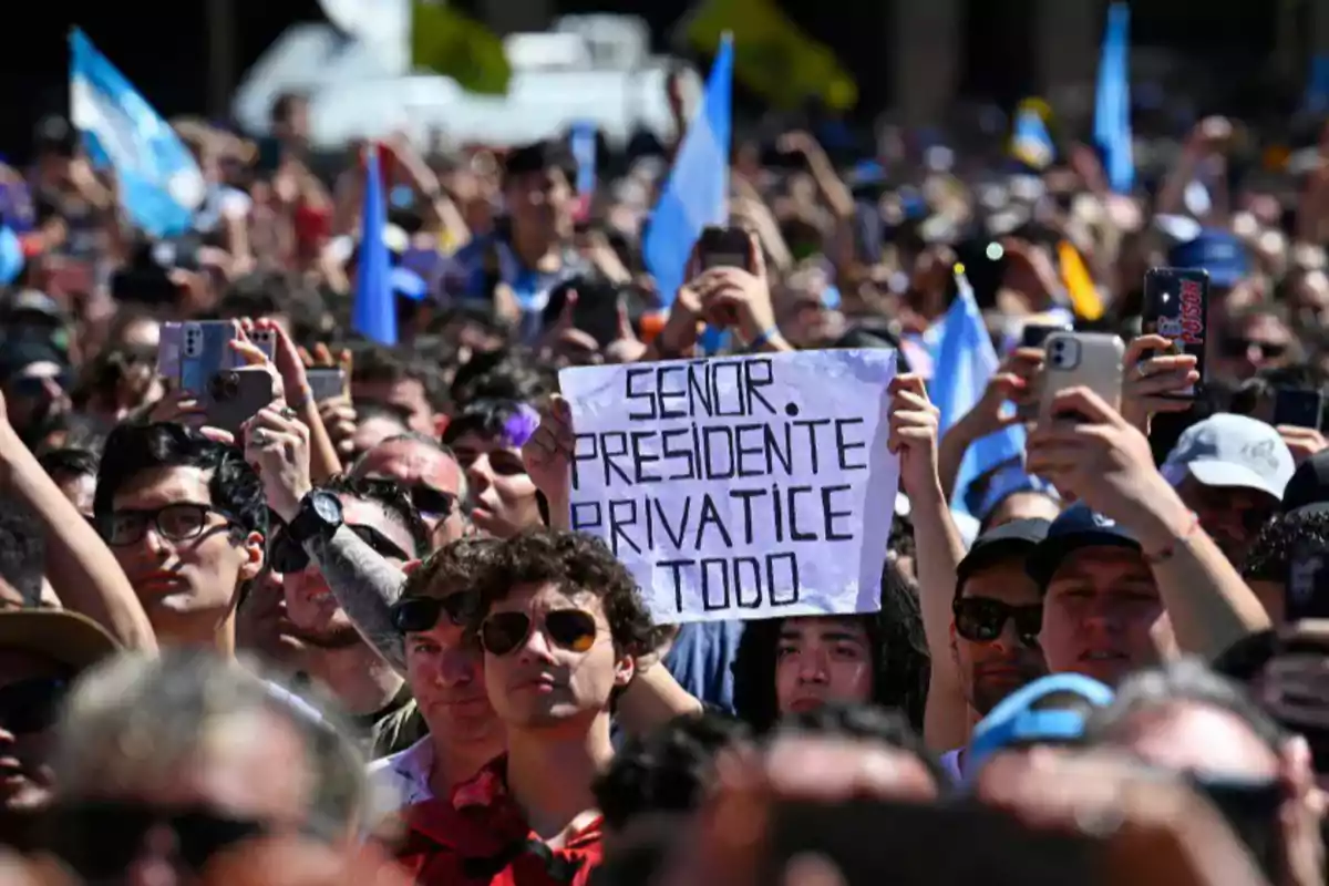 Multitud de personas en una manifestación sosteniendo banderas y un cartel que dice señor presidente privatice todo Multitud de personas en una manifestación sosteniendo banderas y un cartel que dice señor presidente privatice todo