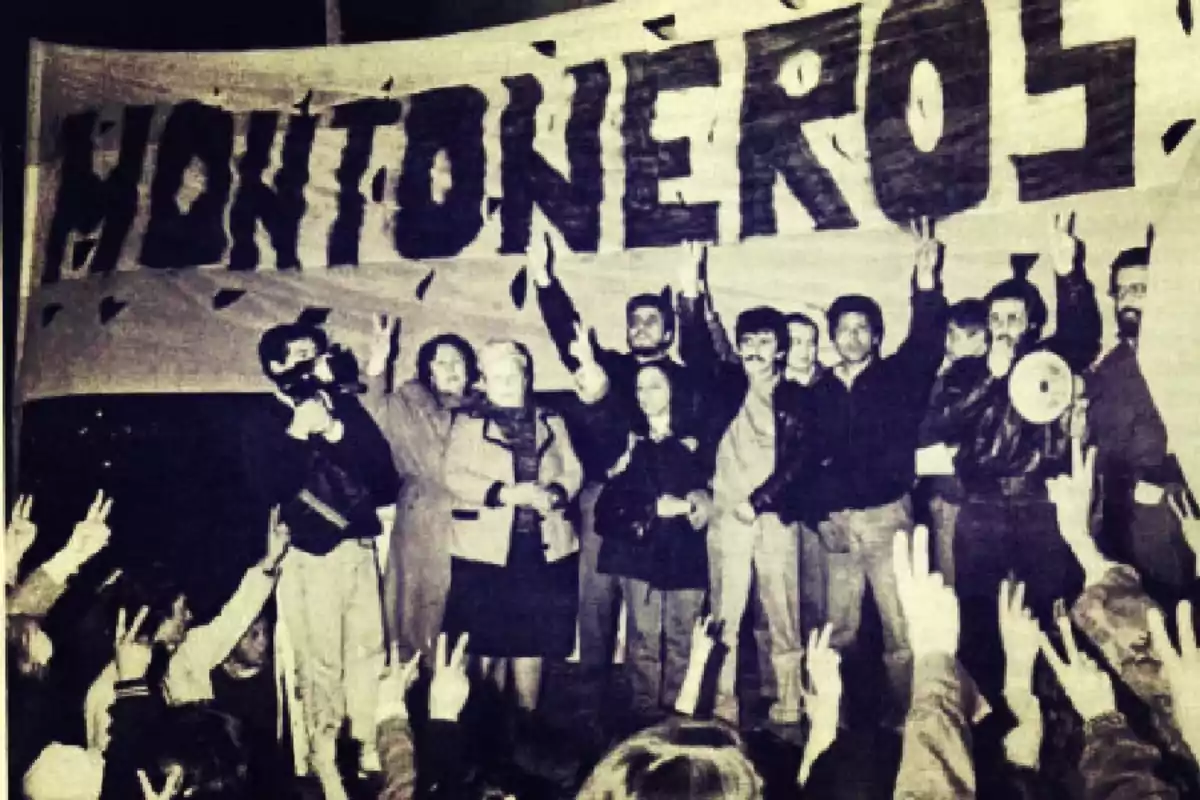Un grupo de personas sobre un escenario levantando los brazos frente a una multitud con un cartel grande que dice Montoneros de fondo Un grupo de personas sobre un escenario levantando los brazos frente a una multitud con un cartel grande que dice Montoneros de fondo