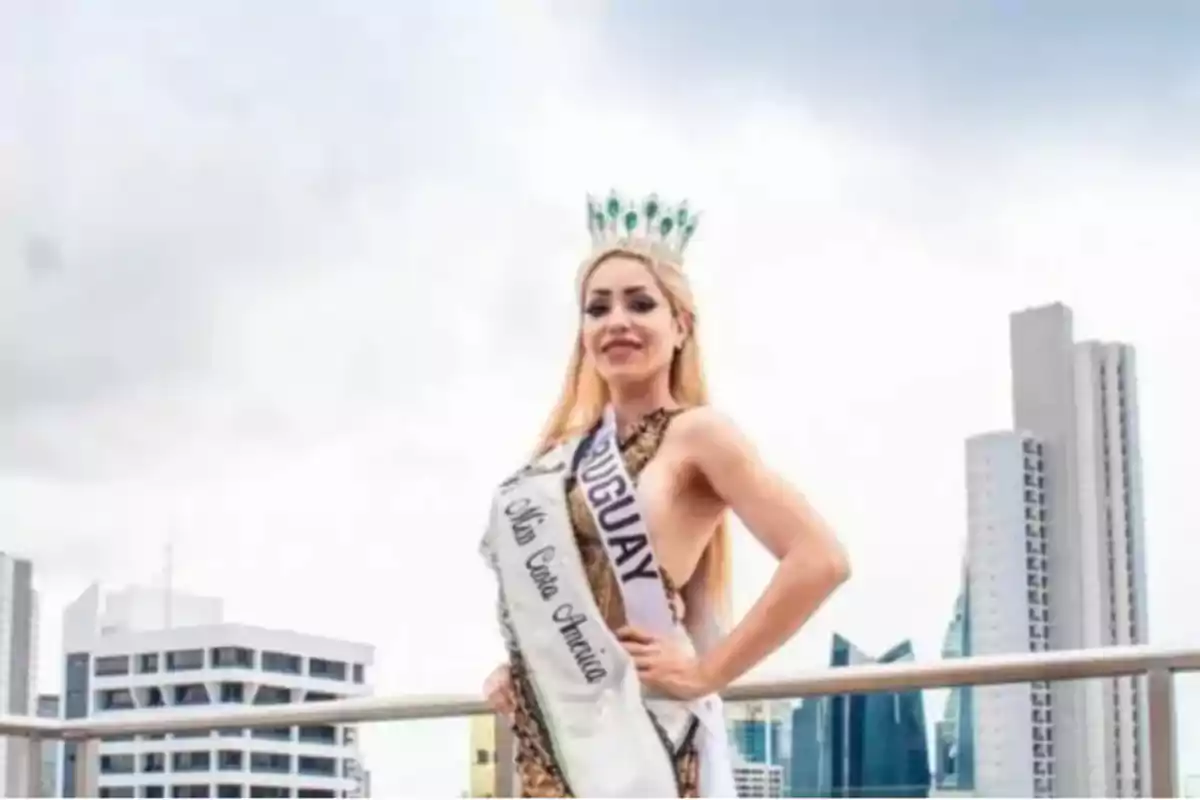 Mujer con corona y banda de concurso de belleza posando en una terraza con edificios altos al fondo Mujer con corona y banda de concurso de belleza posando en una terraza con edificios altos al fondo