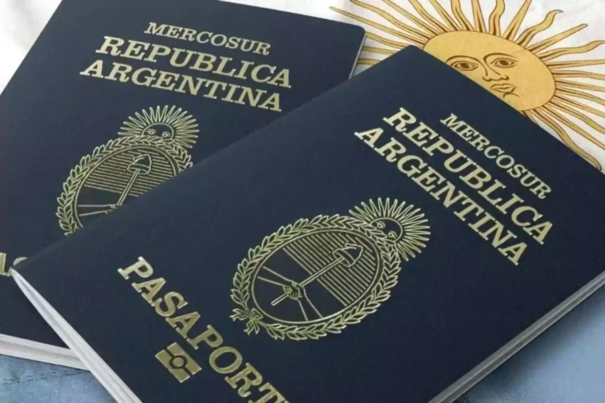 Two dark blue Argentine passports with gold details are resting on a surface next to a flag with a yellow sun.