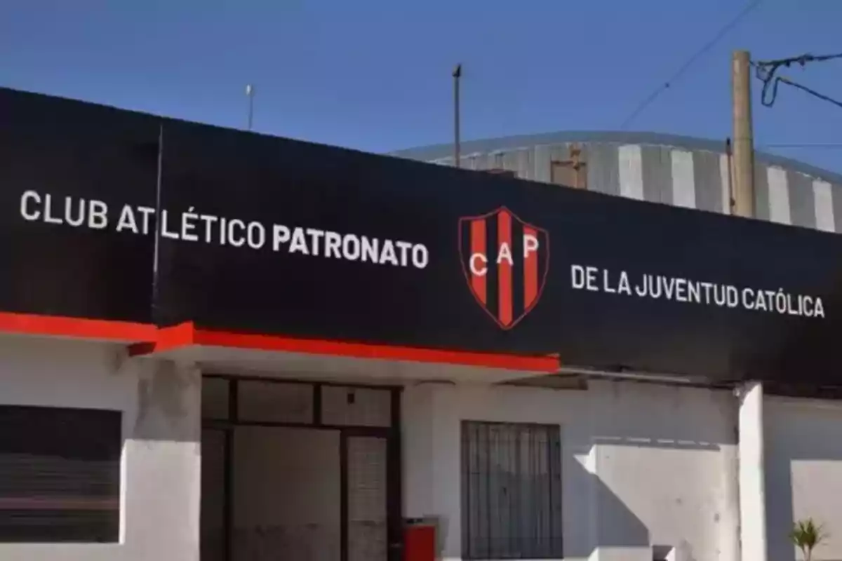 Facade of a building with a black sign that says Club Atlético Patronato de la Juventud Católica and a red and black crest with the letters CAP
