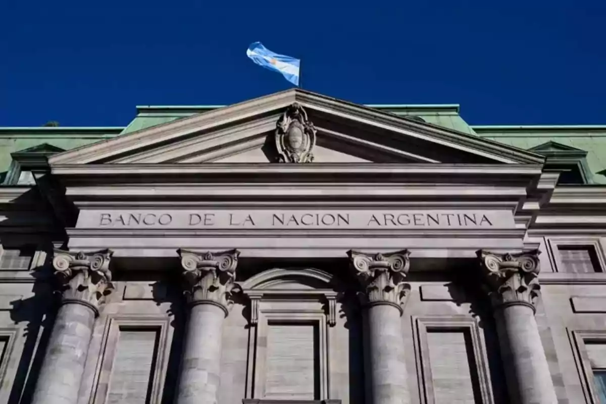 Main facade of the Bank of the Argentine Nation with columns and an Argentine flag waving at the top Main facade of the Bank of the Argentine Nation with columns and an Argentine flag waving at the top