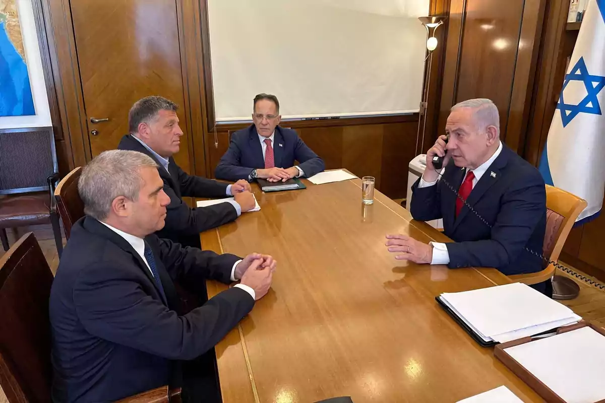 Four men in suits are gathered in a wooden office, one of them is talking on the phone, and there is an Israeli flag in the background. Four men in suits are gathered in a wooden office, one of them is talking on the phone, and there is an Israeli flag in the background.