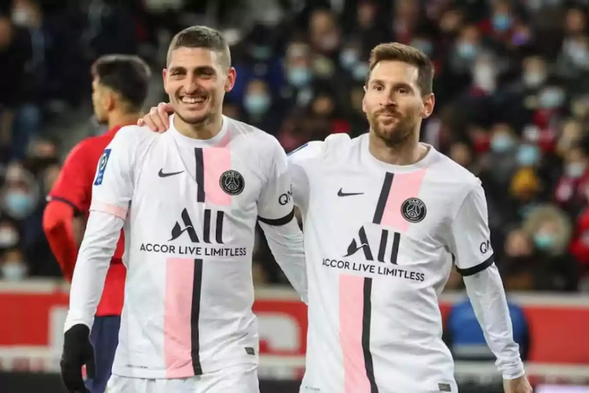 Dos futbolistas del PSG sonríen y caminan juntos en el campo durante un partido Dos futbolistas del PSG sonríen y caminan juntos en el campo durante un partido